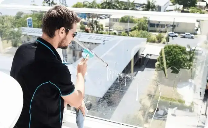 commercial cleaner squeegeeing a window